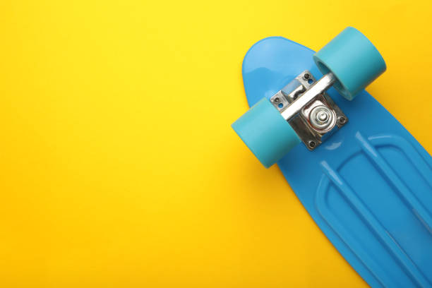 istock Penny Skate board blue with blue wheels on yellow background. Space for text 1387214121