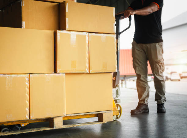 istock Packaging Boxes Stacked on Pallets. Workers Unloading Cartons of Products in the Warehouse.Supply Chain. Shipping Warehouse Logistics. 1387214829