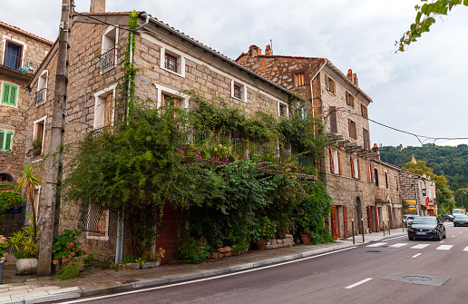 Petreto-Bicchisano, France - August 18, 2018: Old town street view with stone living houses and trees, Corsica island
