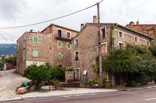 Petreto-Bicchisano, France - August 18, 2018: Corsican old town street view with stone living houses and trees
