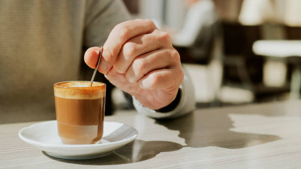 istock man stirs his machiatto with a coffee spoon 1387216884