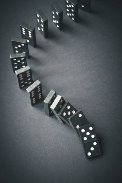 istock Black dominoes chain on dark table background 1387218911