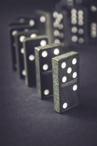 istock Black dominoes chain on dark table background 1387218917