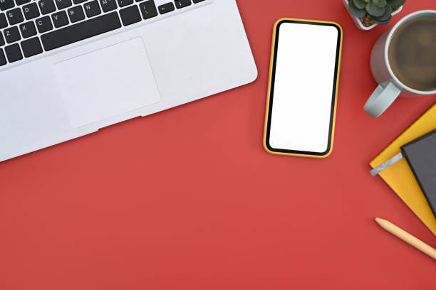 istock Mockup mobile phone with white screen, laptop, notebook and coffee cup on red background. 1387218939