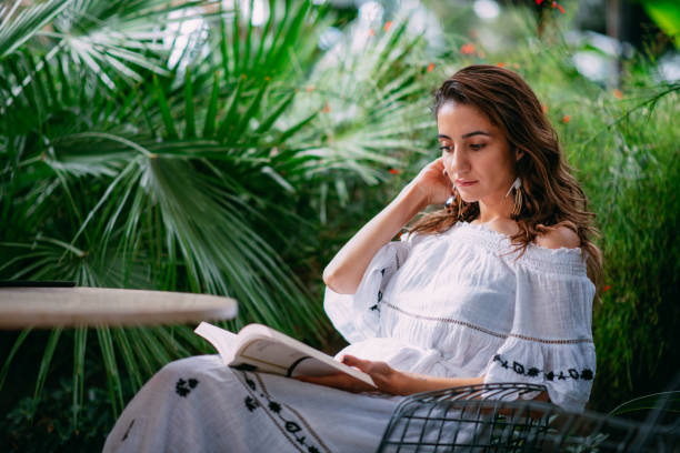 istock Young Woman Reading Book at Cafe 1387220142