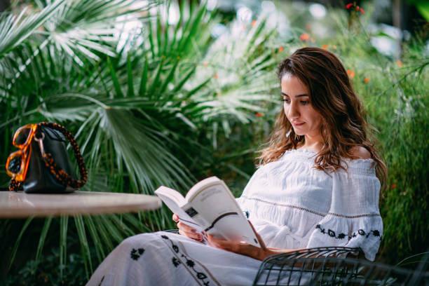 istock Young Woman Reading Book at Cafe 1387220677