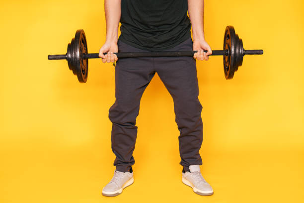 istock Guy holds barbell in his hands against yellow background 1387221858