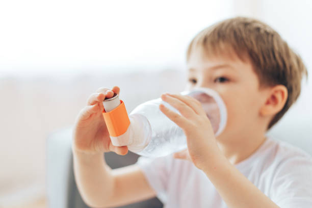 Boy inhales asthma medicine through homemade spacer stock photo