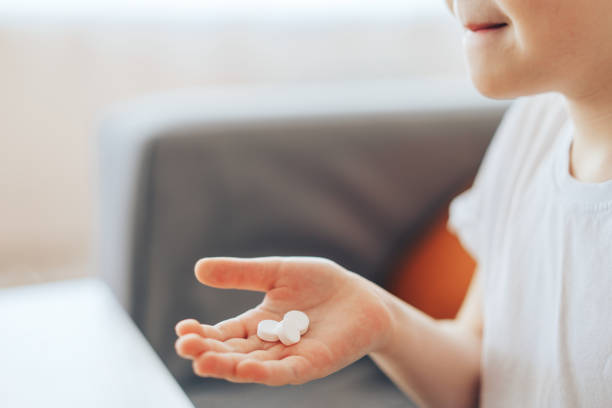 istock Boy holding white pills in his palm 1387221877
