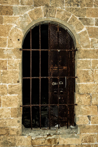 istock antique window with bars in a stone wall 1387222306