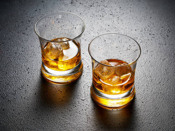 two glasses of elegant whiskey with ice on black textured background. - hard liqueur imagens e fotografias de stock
