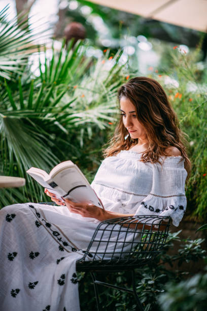istock Young Woman Reading Book at Cafe 1387223560