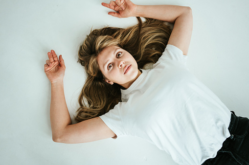 Natural handsome woman in smart casual wear and blond hair lying on the floor, top view