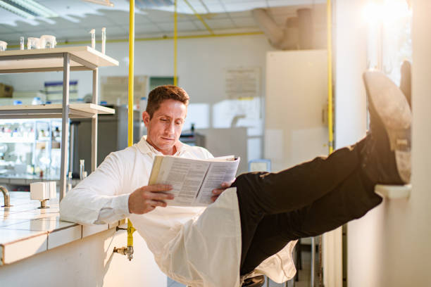 Relaxed scientist reading medical book in laboratory.