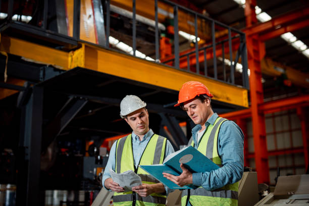 istock Two Maintenance engineers men and women inspect relay protection system with checklist document . They work a heavy industry manufacturing factory. 1387226113