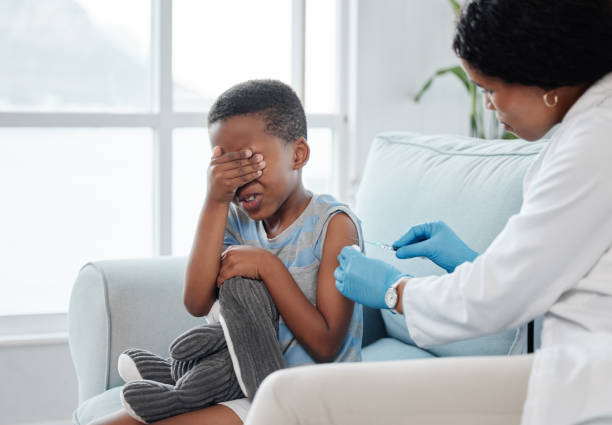 istock Shot of a little boy looking scared while getting an injection on his arm from a doctor 1387226204