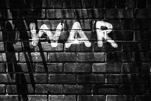 Painted letters on a brick wall spell out the word WAR.