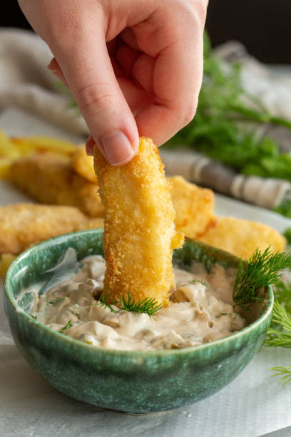 Hand dipping fish finger Hand dipping fish finger in Tartar dip fish stick stock pictures, royalty-free photos & images