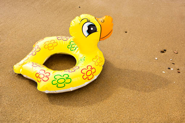 istock Yellow inflatable rubber duck  for children on the sand 1387235497