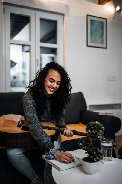 istock Young woman playing acoustic guitar 1387235657