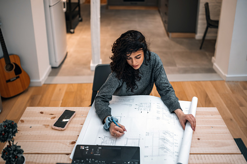 Close up serious focused woman looking at laptop screen, touching chin, sitting at desk, home office, thoughtful businesswoman pondering strategy, working on online project, searching information