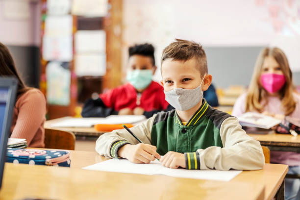 istock A schoolboy sits in class and writes schoolwork during corona virus. 1387243728