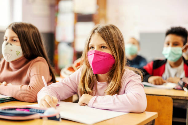 istock A schoolgirl writes schoolwork at class during covid 19. 1387244515