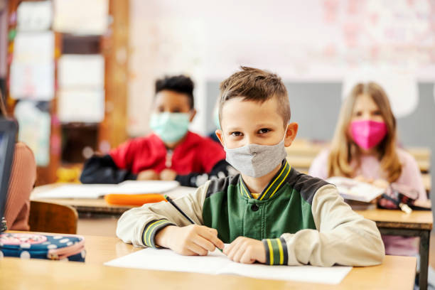 istock Portrait of a pupil writing schoolwork on a class during corona virus. 1387246526