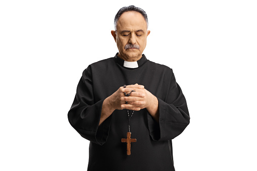 Mature priest holding prayer beads and looking down isolated on white background