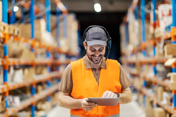 A delivery center worker with voice picking headset scrolling on the tablet. stock photo