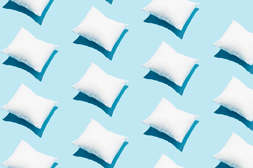 Pattern made of white pillow on serenity pastel blue background. Sleeping concept. Isometric flat lay.