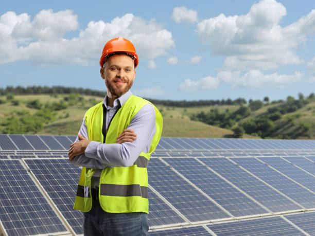 Young male engineer standing on a sustainable solar farm Young male engineer standing on a sustainable solar farm and looking at camera environmental regeneration photos stock pictures, royalty-free photos & images