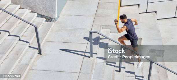 High Angle Shot Of A Sporty Young Man Running Up A Staircase While Exercising Outdoors Stock Photo - Download Image Now