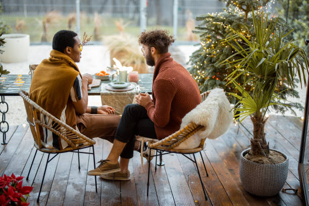 istock Two multiracial male friends having close conversation, sitting by a dinner table at backyard 1387250151