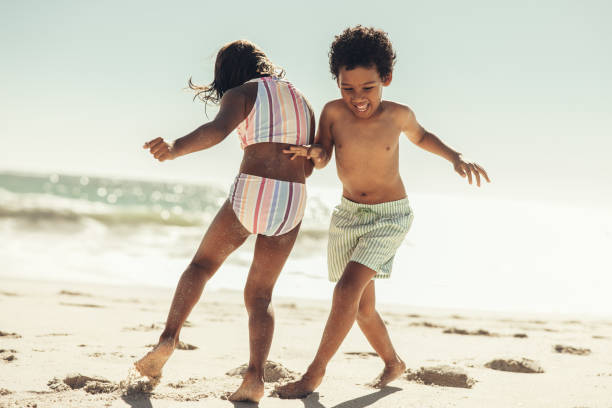 istock Active little kids playing together on beach sand 1387251393