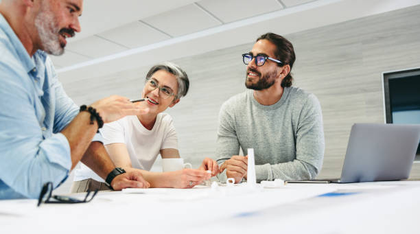 Happy design professionals having a discussion in an office Happy design professionals having a discussion while working on a wind turbine project. Group of innovative businesspeople sharing creative ideas in a modern workplace. industrial designer stock pictures, royalty-free photos & images