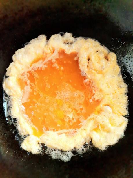 istock Cooking Fried Egg Omelet in cooking pan - food preparation. 1387251762