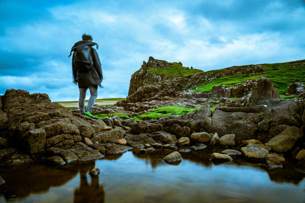 Hiking to Duntulm Castle on the Isle of Skye, Scotland A man hiking to the Duntulm Castle from the water looks beneath, on the Isle of Skye scottish highlands castle stock pictures, royalty-free photos & images