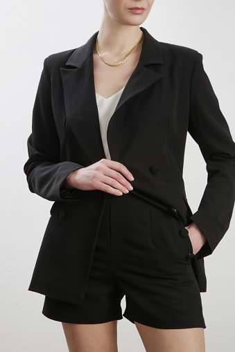 Female model wearing black tailored blazer and short pants. Studio shot.