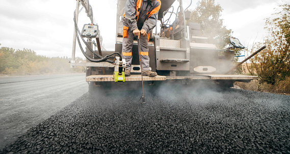 Vibratory asphalt roller compactor compacting new asphalt pavement. Road service repairs the highway