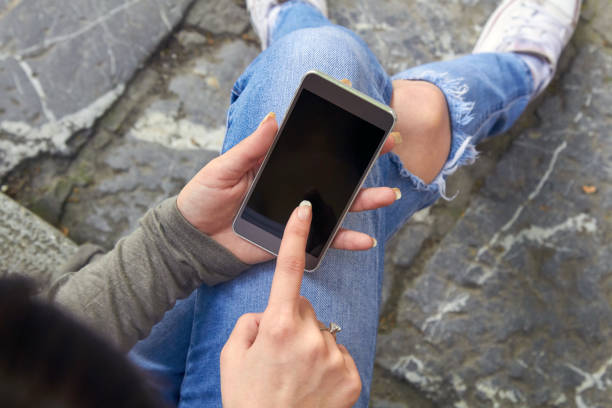 istock Woman in jeans using modern smartphone outdoors. 1387255200