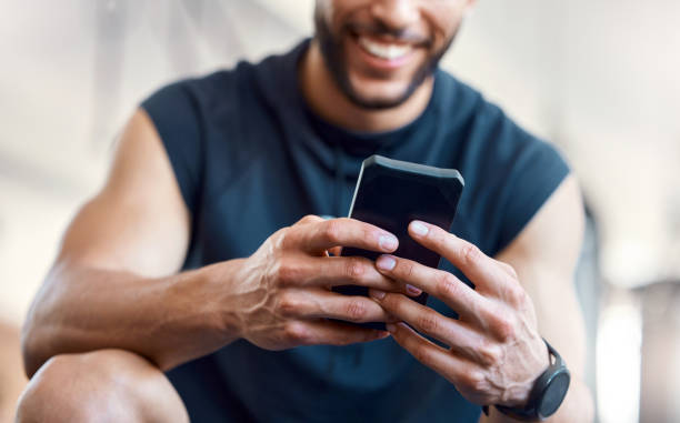Low angle shot of an unrecognisable man using a cellphone in a gym
