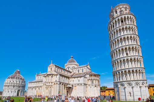 Tourists visiting the famous Piazza dei Miracoli, formally known as Piazza del Duomo, the iconic artistic center of Pisa, listed as a UNESCO World Heritage Site since 1987.