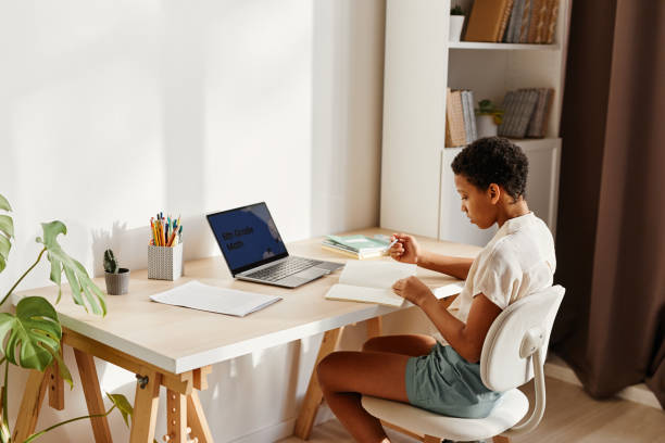istock Young Black Girl Studying at Desk in Sunlight 1387257124