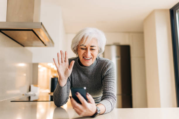 istock Cheerful elderly woman waving her hand during a video call 1387258341