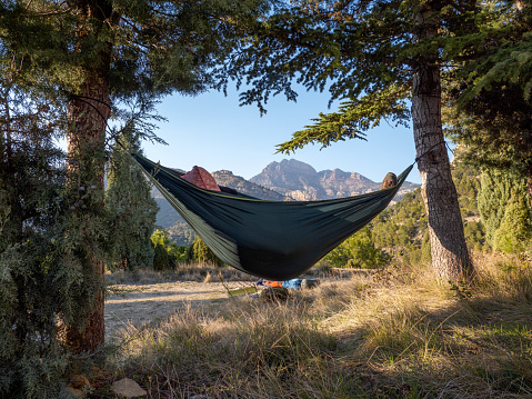 Person resting on a hammock between two trees in the mountains