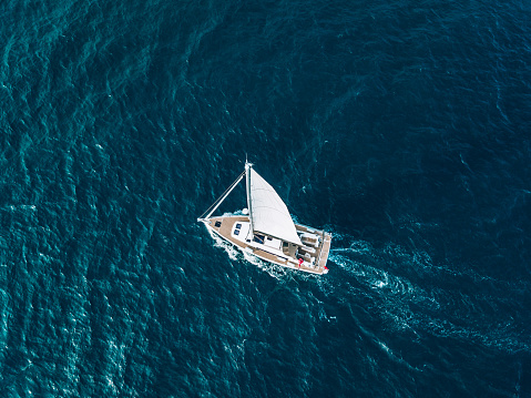 Aerial view of luxury yacht sailing on a blue sea in Italy.