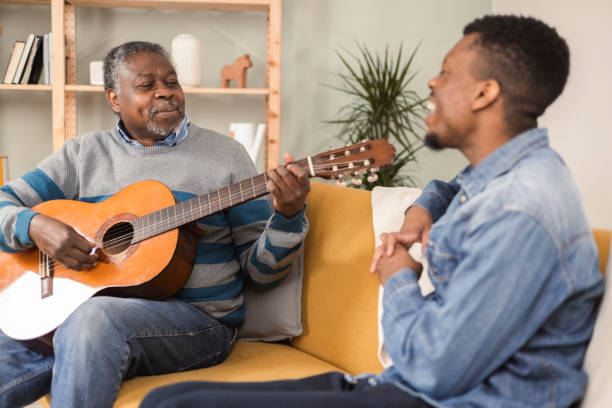 istock Senior African American man playing a guitar and amusing his son 1387259311