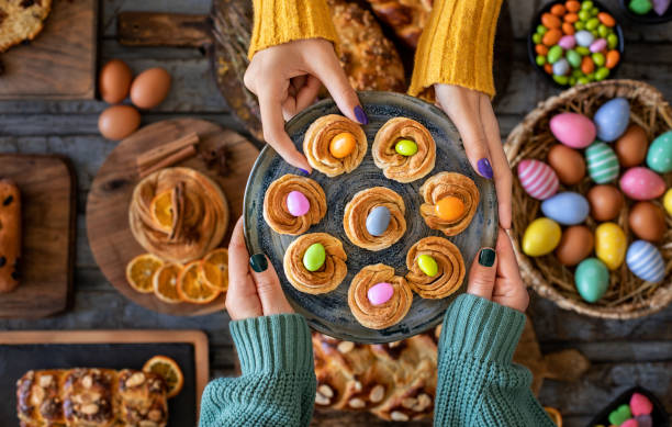 Hand of two women with Easter buns and Easter eggs. Paskalya çöreği . Easter concept with table top view. orthodox church easter stock pictures, royalty-free photos & images