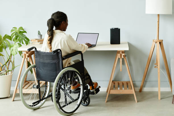 istock Woman in Wheelchair Working from Home Minimal 1387262003